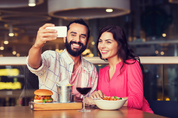 couple taking selfie by smartphone at restaurant