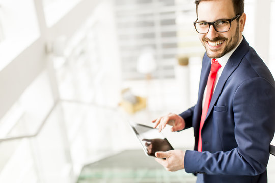 Young man with tablet on stairs in modern office - Powered by Adobe