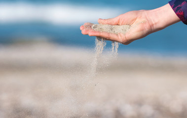 Sand slip through girl's fingers on the beach