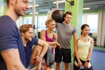 group of friends with sports equipment in gym