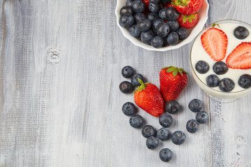 Strawberry, blueberry with yogurt on a gray wooden background
