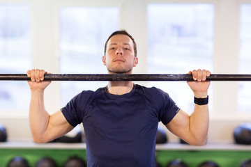 man exercising on bar and doing pull-ups in gym