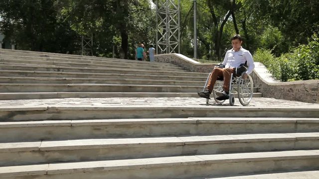 Young disabled man in wheelchair in front of stairs. He can't come down