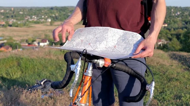Cyclist with map on top of the mountain
