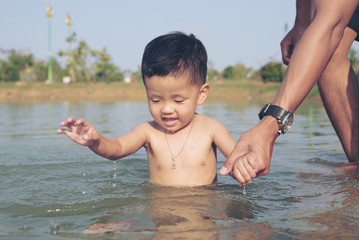 Happy baby and father playing at the Lake. Happy family playing in water of Lake on a tropical resort at the nature.