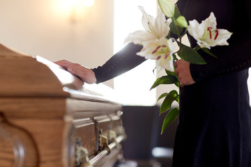 woman with lily flowers and coffin at funeral - obrazy, fototapety, plakaty