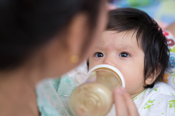 Mother feeding newborn son with feeding bottle