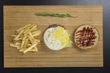 Uncovered tasty burger with fried eggs and potato's on the table