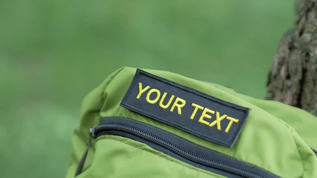 On the green backpack stick a patch with the inscription your text. Yellow letters on a black background