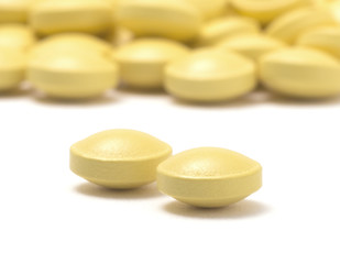 Fototapeta na wymiar Heap of yellow pills isolated on a white background