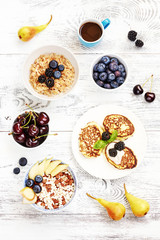 Healthy summer breakfast top view.  Oatmeal with blueberry, bowl of puffed rice cereal with pear, ricotta fritters, cup of coffee, fresh berries on white table.