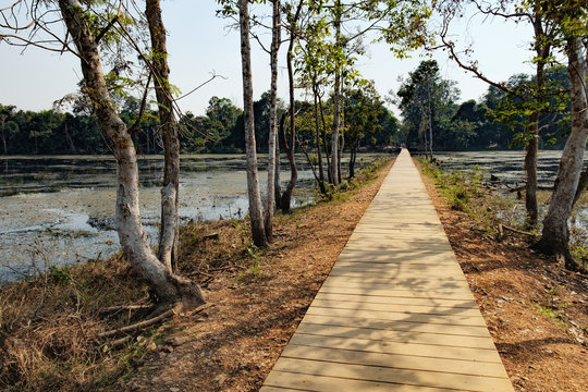 Mysterious wooden path towards Neak Pean Temple through artificial island in Angkor Complex, Siem Reap, Cambodia. Ancient Khmer architecture, famous Cambodian landmark, World Heritage