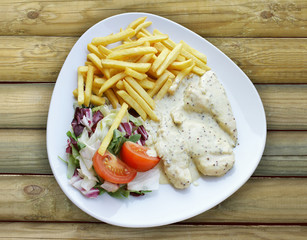 Plate with aromatic chicken breasts flavored with spices and sauce french fries mixed salad