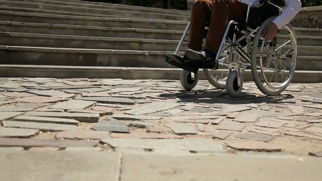 Close up of young disabled man in wheelchair in front of stairs.