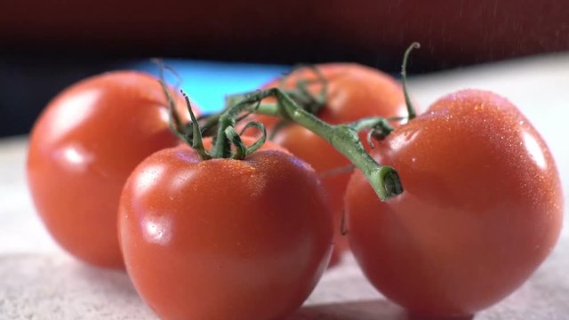 Detail of ripe tomatoes being sprayed with water in slow motion
