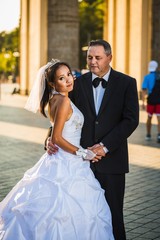Portrait of a happy multicultural wedding couple at Brandenburger Gate with back sun light. Newlyweds.  © arianarama