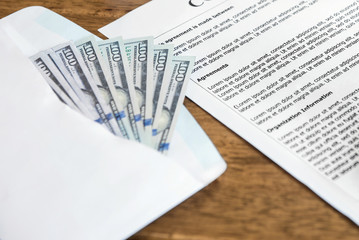 Money (US dollar bills) on the table beside contract paper