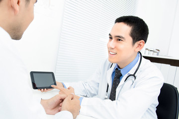 Physician talking  and explaining treatment to patient by using tablet computer