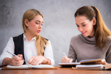 Two pretty women studying together in a library  