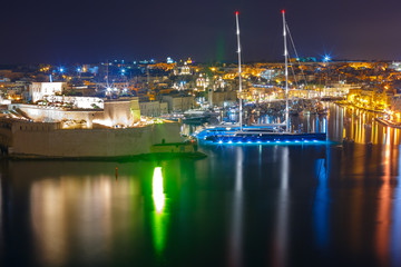 Obraz na płótnie Canvas Aerial skyline view of ancient defences of Birgu and Fort St. Angelo, as seen from Valletta at night, Malta.