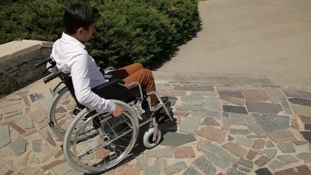 Young disabled man in wheelchair in front of stairs. He can't come down
