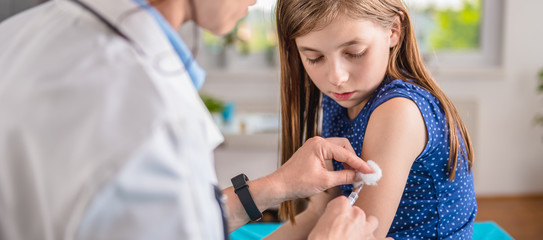 Doctor giving a young girl a vaccine shot
