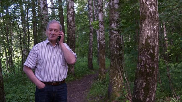 Elderly Man Talking On The Phone In The Summer Forest