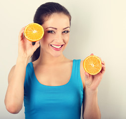 Beautiful toothy smiling fit young healthy casual woman holding slices of oranges in the hands. closeup portrait . Toned