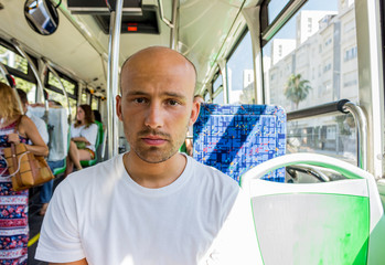 Portrait of young bald man riding on a bus close up