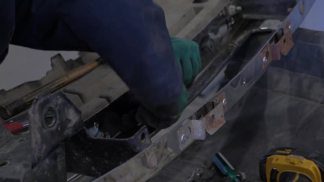 A Mechanic Pulling A Rivet Out Of A Car Bumper