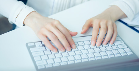 Closeup picture of female hands typing on desktop computer keyboard.