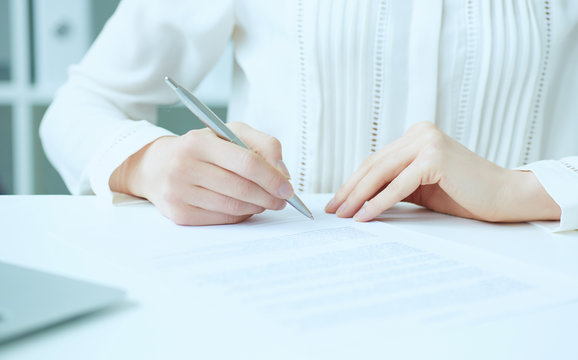 Businesswoman hands sign contract on desk. Female entrepreneur puts signature on official agreement. Profitable deal concept. Business partner accepts conditions. Shallow focus on signature.