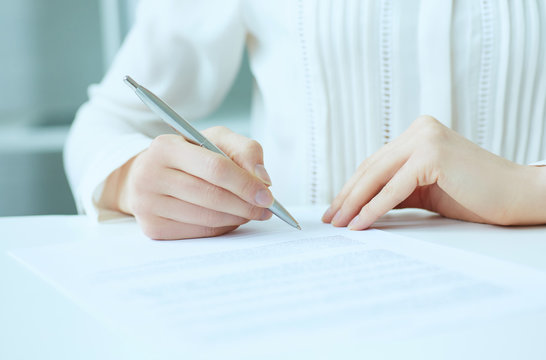 Businesswoman hands sign contract on desk. Female entrepreneur puts signature on official agreement. Profitable deal concept. Business partner accepts conditions. Shallow focus on signature.