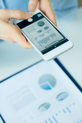 Closeup of women's hands taking photo of business charts.