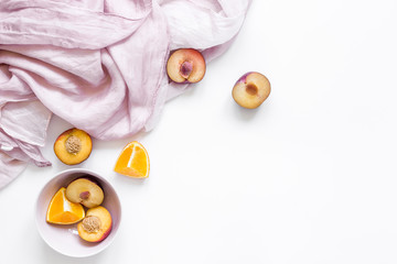 tropical fruits design with orange and peach on fabric white table background top view mock up