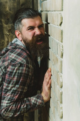 Angry bearded man screaming at brick wall