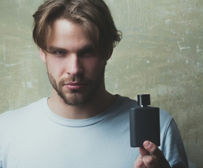 Handsome man posing with black perfume bottle