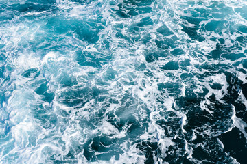 Natural background of blue-green sea water with foam and waves.