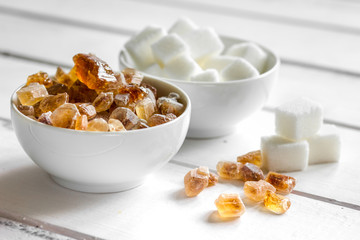 lumps of white and brown sugar on white wooden table background