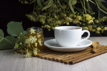 White cup with linden tea, a jar of honey and a spoon