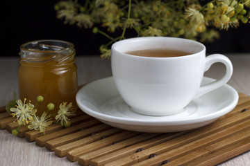 White cup of tea with linden flowers, honey