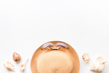 Sunglasses, straw hat and seashells on a white background with place for text