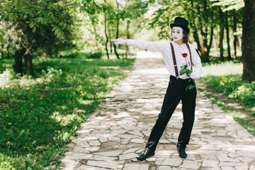 Emotional male mime artist with red rose performing love on a outdoor.