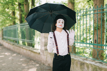 Emotional male mime artist with umbrella.