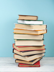 Open stacking book, hardback colorful books on wooden table and blue background. Back to school. Copy space for text. Education business concept.