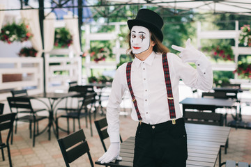 Emotional male mime artist with red rose posing on the summer terrace at the restaurant