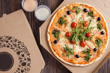 Thin crust pizza with seafood in cardboard delivery box