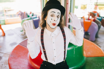 A funny pantomime from a circus rides a swing.