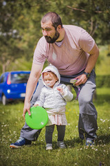 Naklejka na ściany i meble Young dad and his little daughter playing Frisbee in the park
