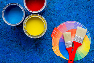 Colorful paints and brushes on blue wooden desk background top view copyspace